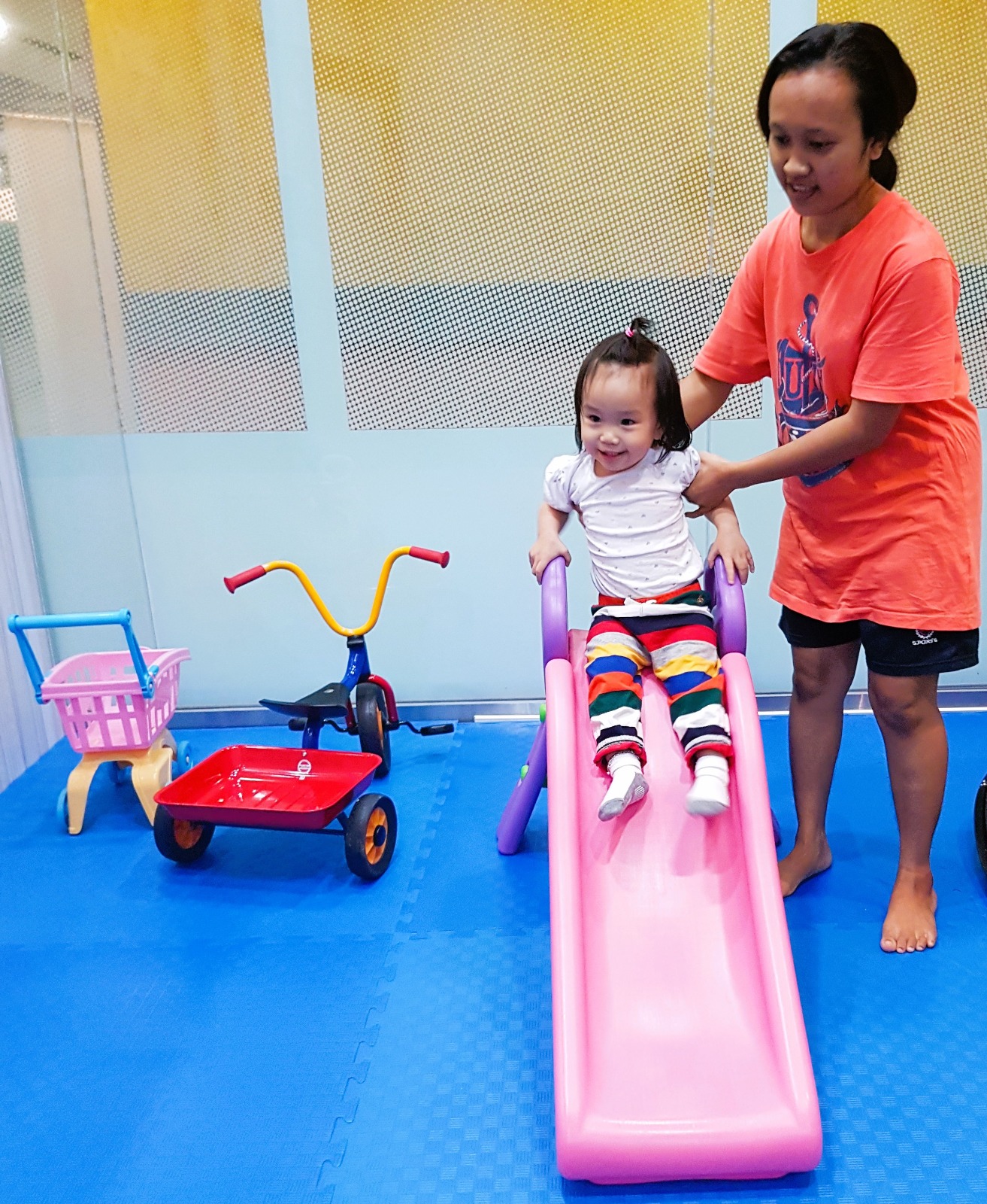 Helper playing with a toddler at a slide